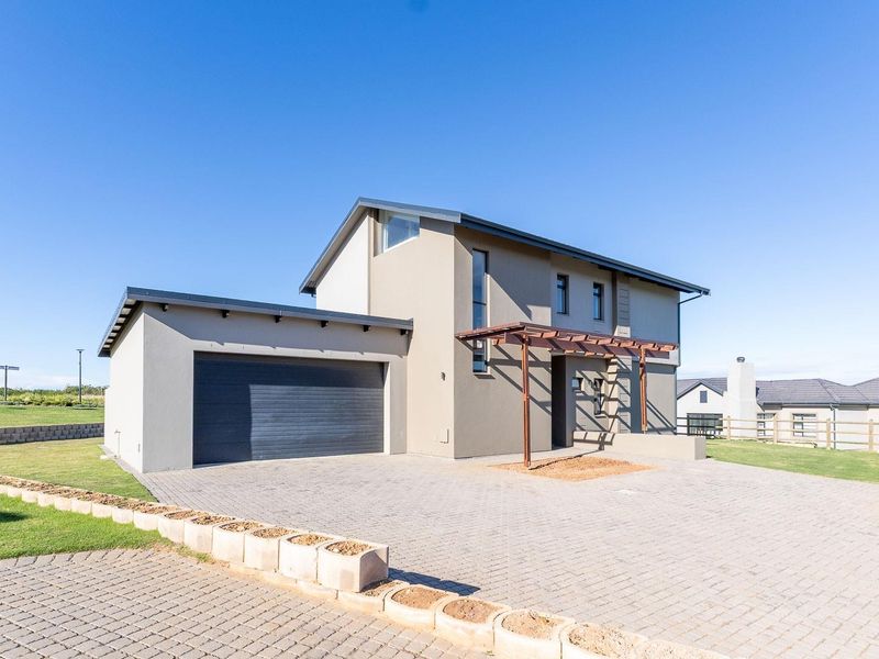 Modern double-story house featuring a paved driveway, attached double garage, and a timber pergola entrance, set within a well-maintained landscaped garden.