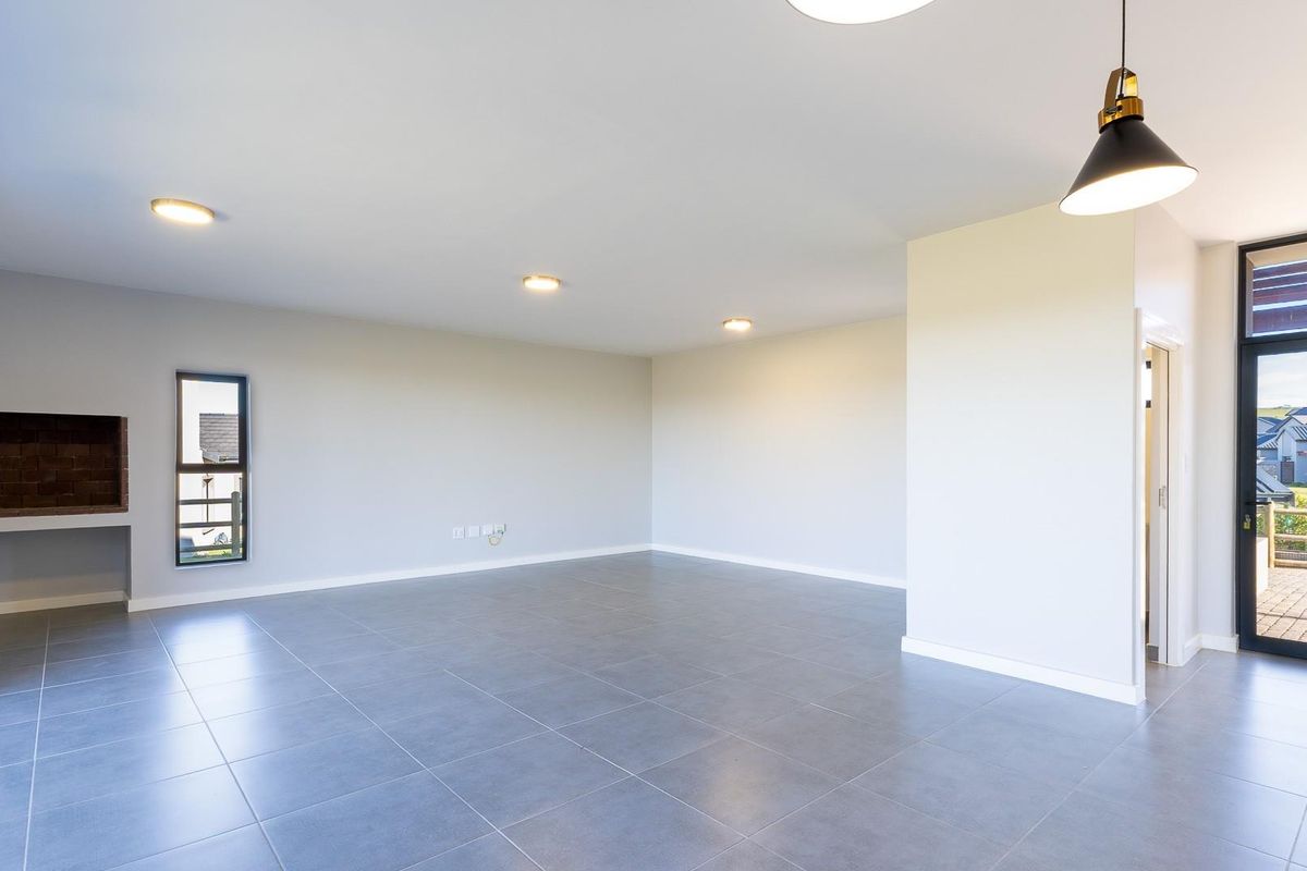 Spacious, modern open-plan living area featuring large format floor tiles, recessed lighting, a built-in fireplace, and direct access to an outdoor patio.
