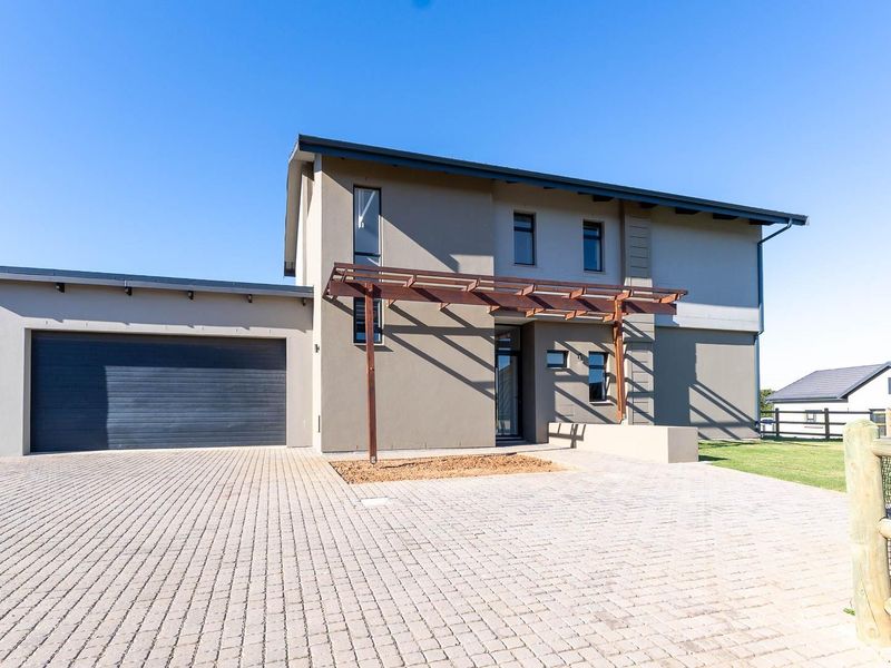 Modern double-story residential home featuring a paved driveway, integrated double garage, and a decorative timber pergola at the entrance.