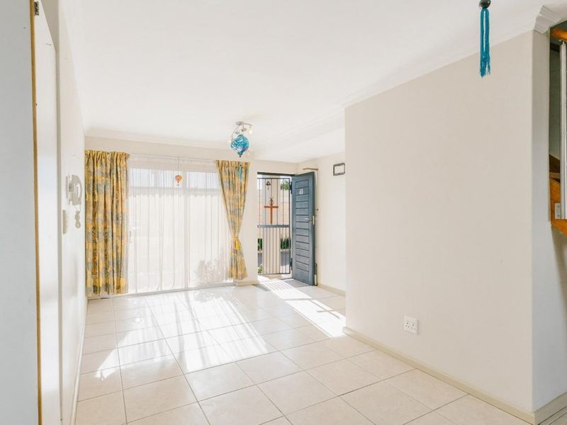 Bright entrance area featuring tiled flooring, a timber staircase with stainless steel balustrade, and direct access to the exterior through a sliding glass door.