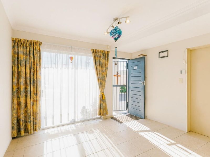 A bright and spacious entrance area featuring tiled flooring, a secure entrance door with an integrated security gate, and a large sliding glass door.