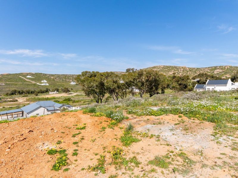 A view of the vacant residential land featuring natural vegetation and a gentle slope, overlooking the surrounding landscape and neighboring properties.