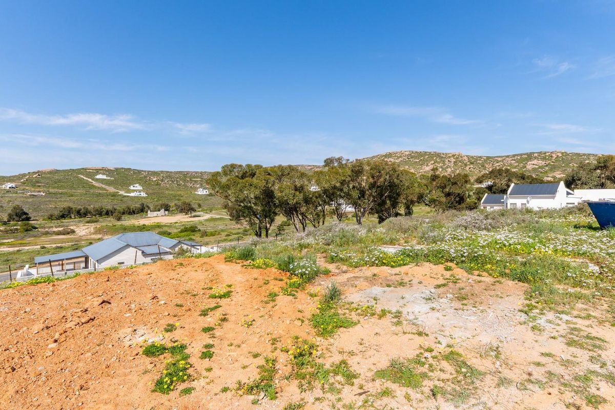 A view of the vacant residential land featuring natural vegetation and a gentle slope, overlooking the surrounding landscape and neighboring properties.