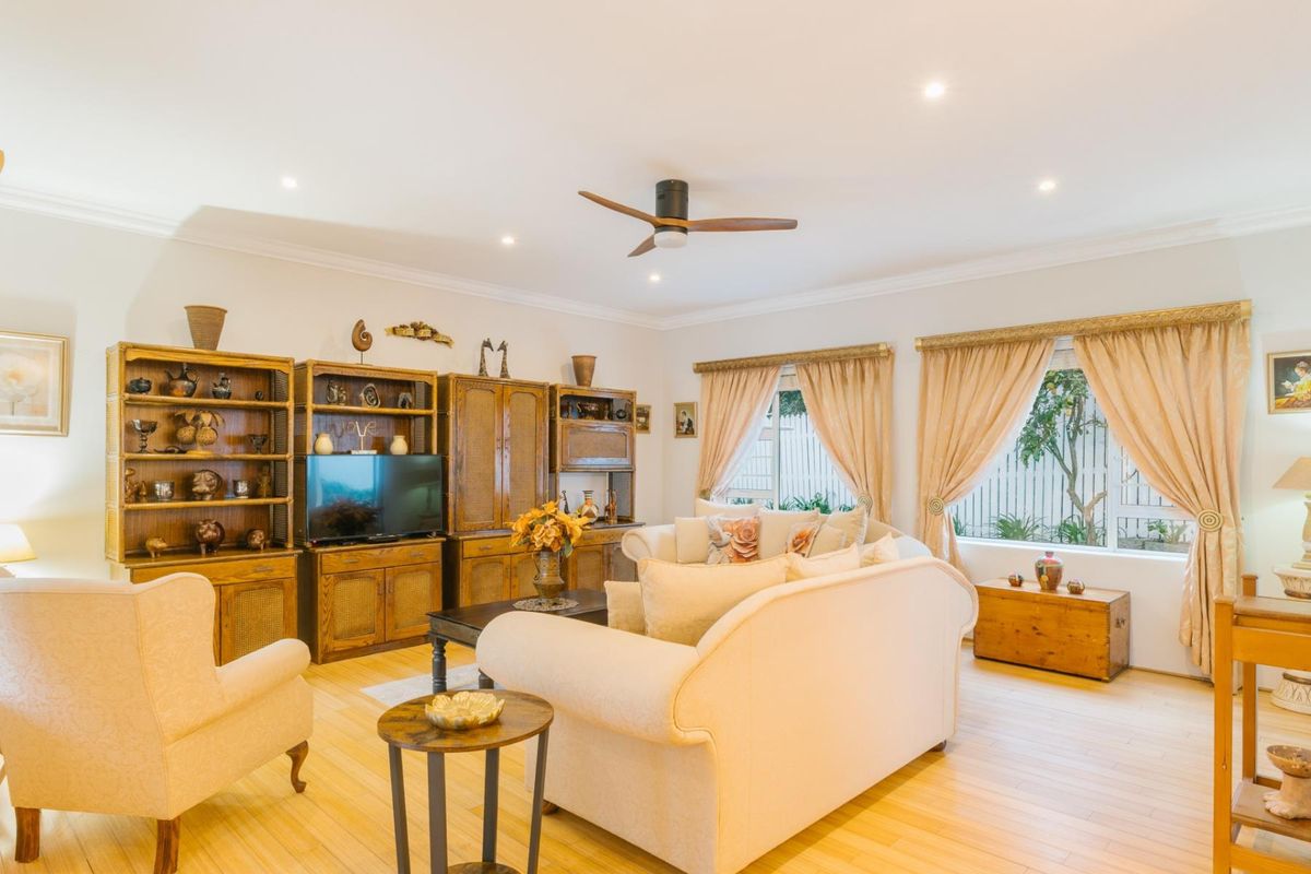 A well-maintained living room featuring timber flooring, recessed downlights, and a ceiling fan, offering a comfortable and inviting atmosphere.