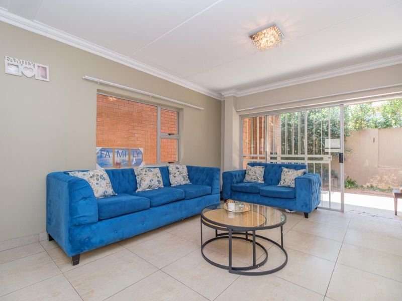 A bright living room featuring neutral tiled flooring, cove cornicing, and a sliding glass door providing direct access to the outdoor area.