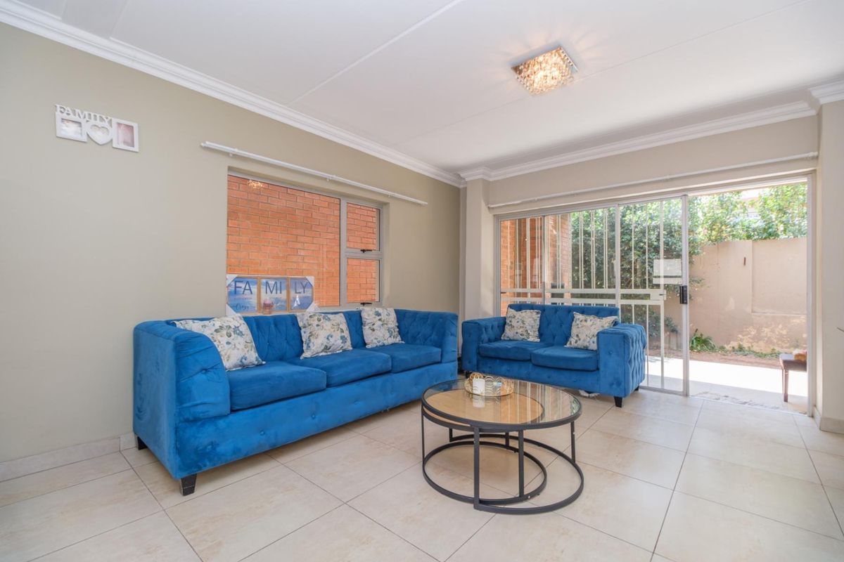 A bright living room featuring neutral tiled flooring, cove cornicing, and a sliding glass door providing direct access to the outdoor area.