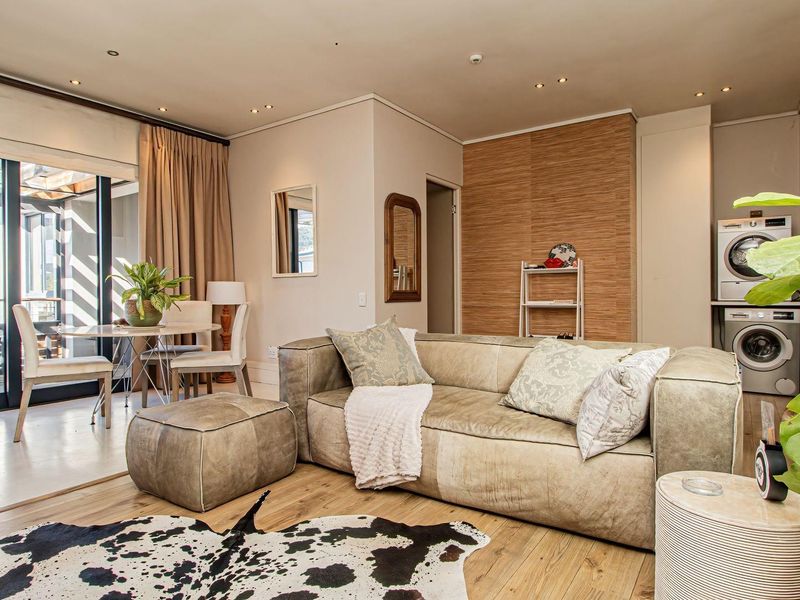 An open-plan living and dining area featuring laminate flooring, recessed lighting, and a convenient built-in laundry space with integrated appliances.