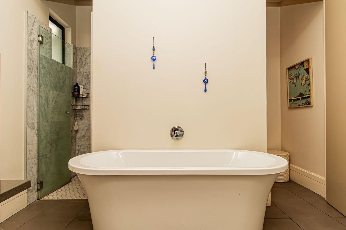 Modern bathroom featuring a sleek freestanding bathtub, a walk-in shower with marble tiling, and a wall-mounted heated towel rail.