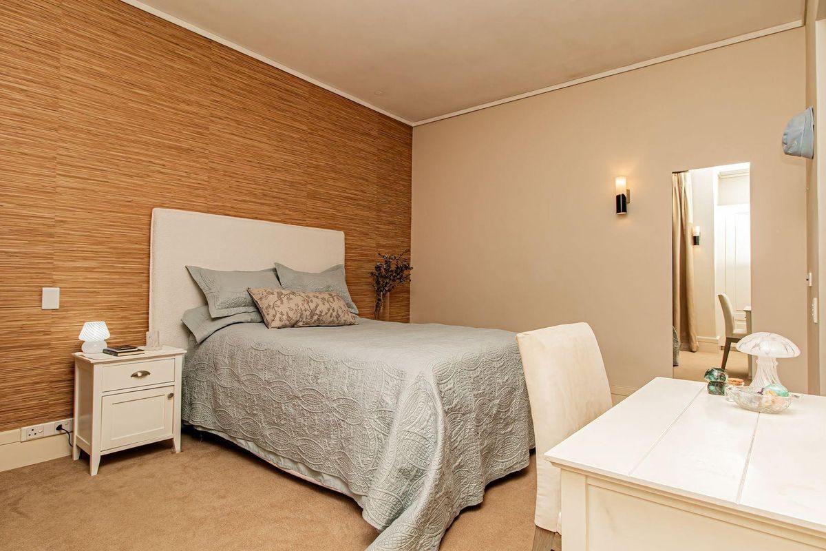 A well-maintained bedroom featuring a textured wood-look feature wall, neutral carpeting, and integrated wall lighting.
