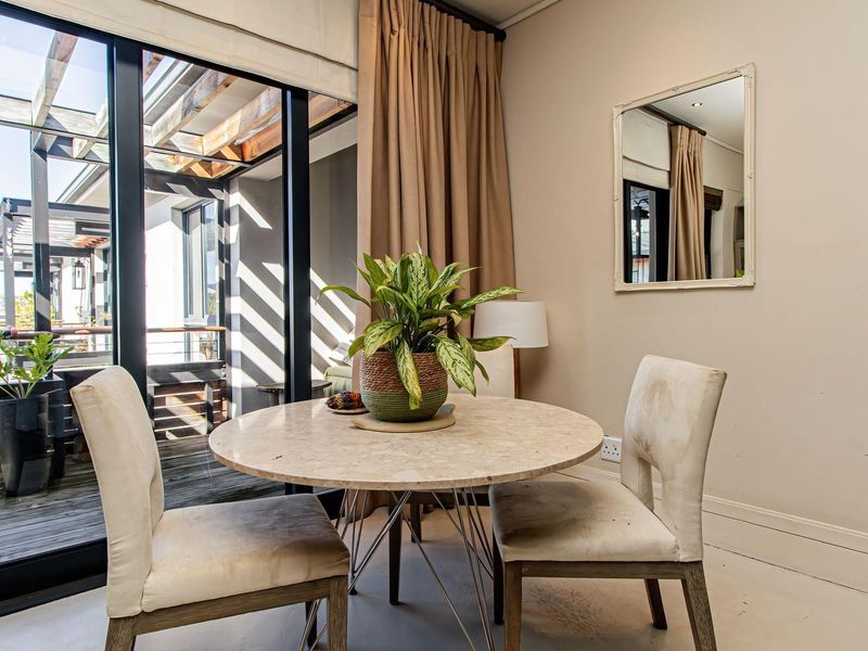 A bright dining area featuring large sliding glass doors that open onto a wooden deck, providing ample natural light and seamless indoor-outdoor flow.