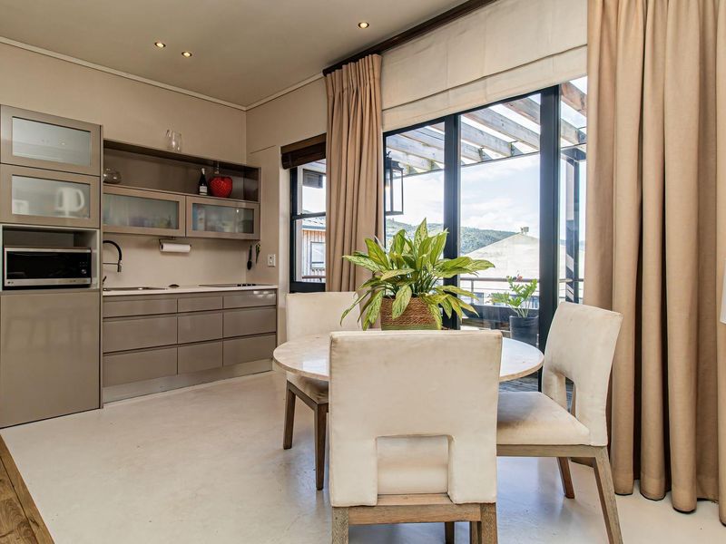 Open plan kitchen and dining area featuring modern built-in cabinetry, recessed lighting, and large sliding doors opening to a covered outdoor patio.