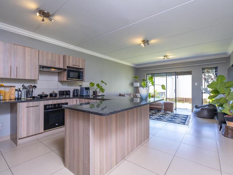 Open-plan living area featuring a modern kitchen with granite countertops, built-in appliances, and seamless flow to the outdoor patio through sliding glass doors.