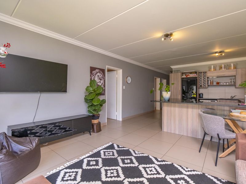 Open plan living area featuring tiled floors, neutral walls, and a modern kitchen with granite countertops and wood-finish cabinetry.