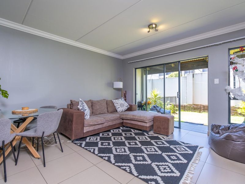 Open-plan living and dining area featuring neutral tiled flooring, crown molding, and large sliding glass doors providing direct access to the rear patio.