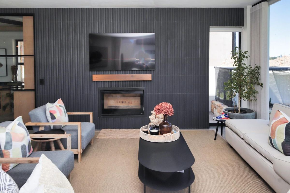 Modern living room featuring a striking dark textured feature wall with a built-in fireplace and seamless access to an outdoor area.