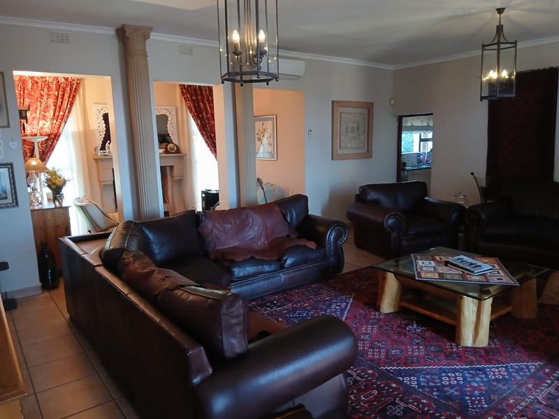 Spacious living area featuring decorative columns, tiled flooring, and classic pendent lighting, offering a traditional layout with access to adjacent rooms.