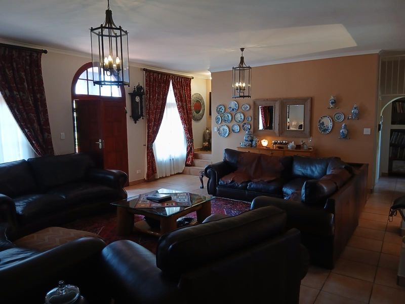 Spacious living room featuring tiled flooring, arched timber entrance door, and decorative pendant lighting, offering a comfortable and traditional living space.