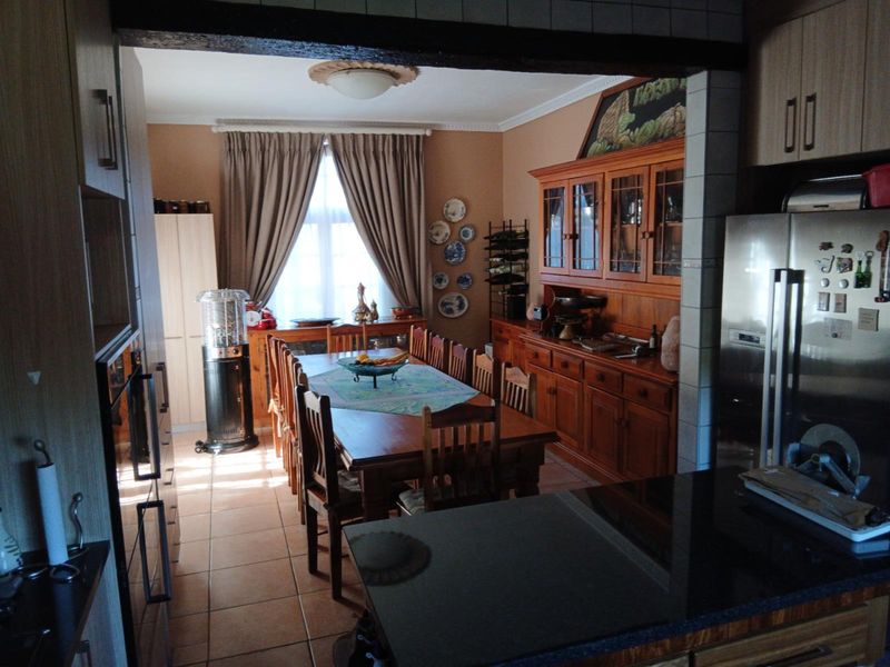 Open plan kitchen and dining area featuring tiled flooring, granite countertops, and extensive built-in wooden cabinetry.