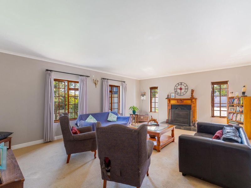 Spacious living room featuring a classic wooden fireplace mantel, timber-framed windows, and neutral carpeting, offering a comfortable and traditional atmosphere.
