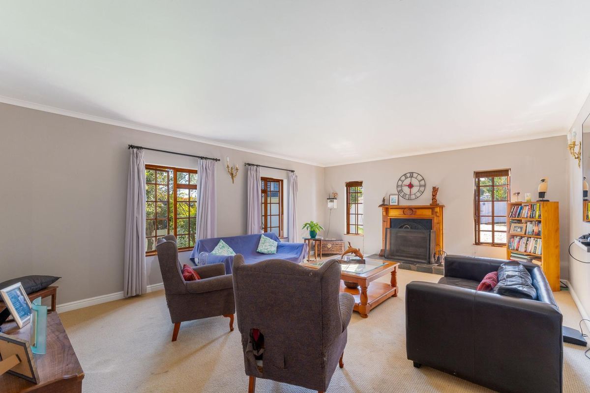 Spacious living room featuring a classic wooden fireplace mantel, timber-framed windows, and neutral carpeting, offering a comfortable and traditional atmosphere.