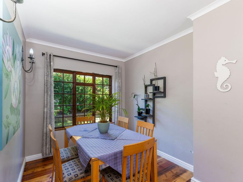 A well-maintained dining room featuring warm hardwood flooring, classic timber-framed windows, and neutral wall tones, providing a cozy and inviting space for meals.