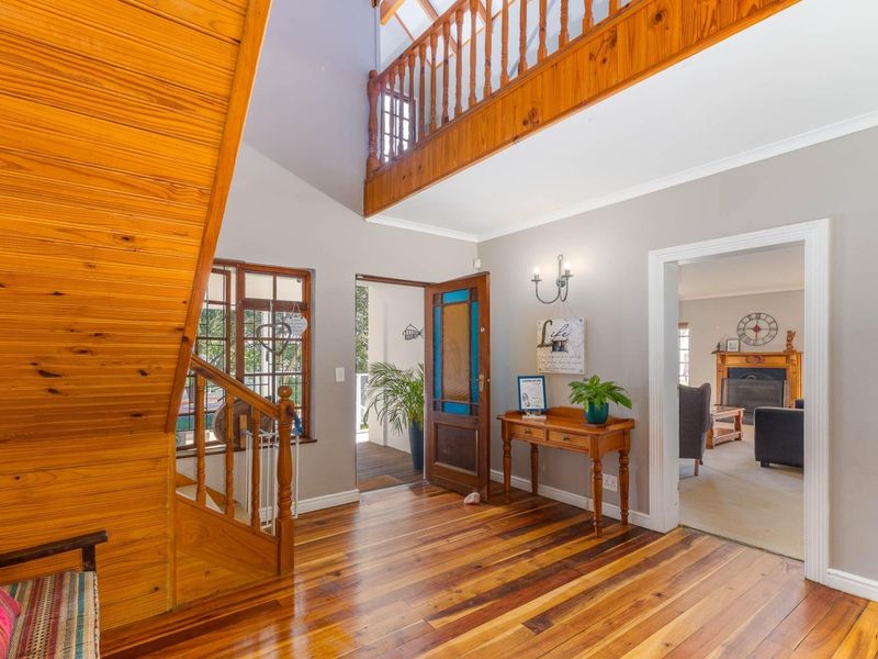 Welcoming entrance hall featuring warm timber flooring, a prominent wooden staircase, and a mezzanine landing overlooking the foyer.