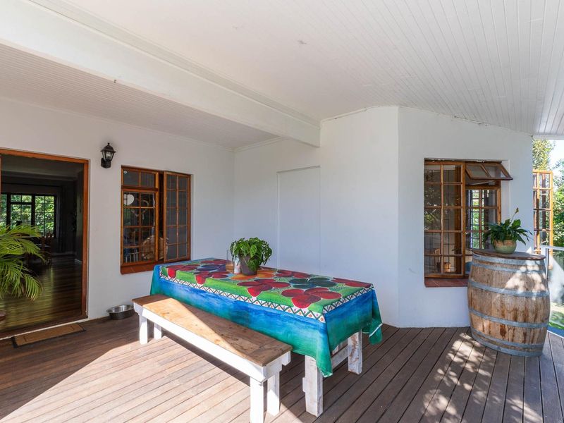 A covered outdoor patio featuring timber decking, beadboard ceiling, and direct access to the interior living space through a timber-framed door.