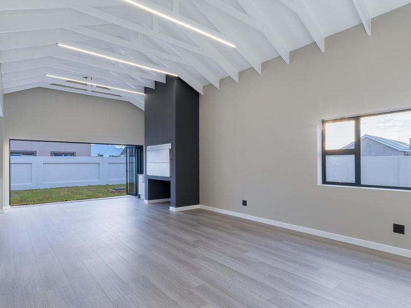Spacious open-plan living area featuring a vaulted ceiling with exposed rafters, built-in fireplace, and large bi-fold doors opening to the rear garden.