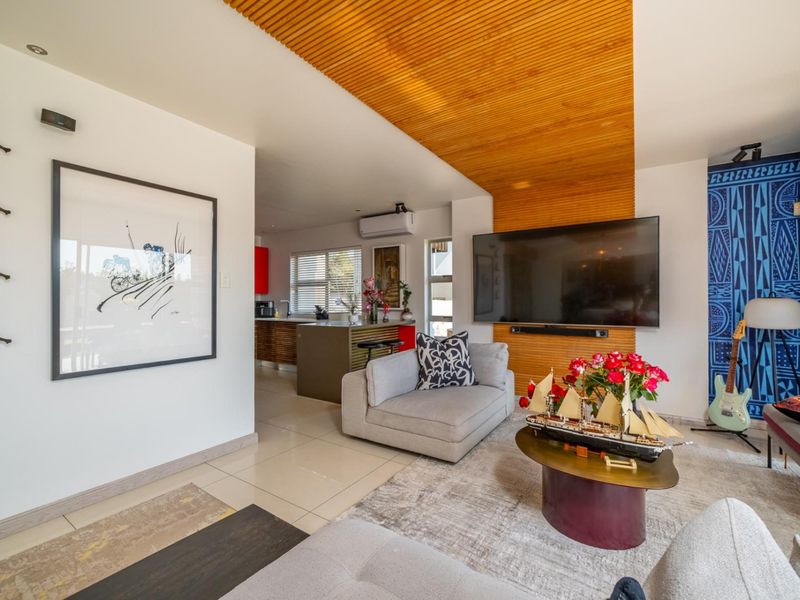 Open plan living area featuring a striking timber slat ceiling detail, tiled flooring, and a seamless transition into the adjacent kitchen space.