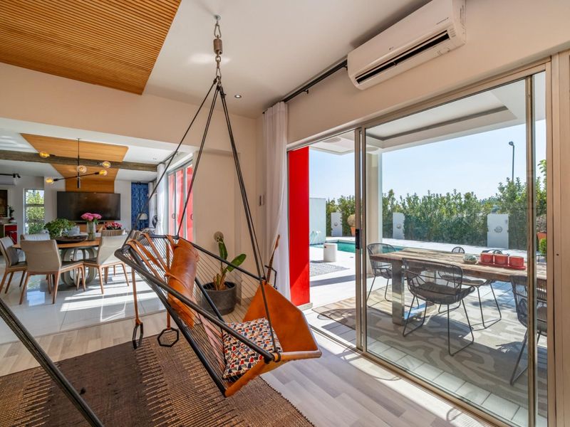 Modern open-plan living area featuring a slatted timber ceiling, split-system air conditioning, and seamless flow to an outdoor patio and pool area.