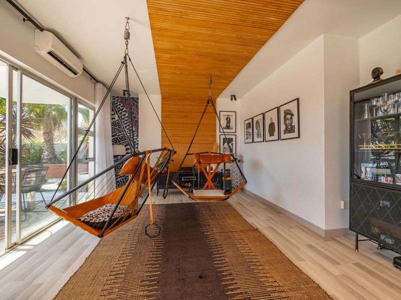 Modern living room featuring a distinctive timber slat ceiling, laminate flooring, and large sliding glass doors providing seamless access to the outdoor patio area.