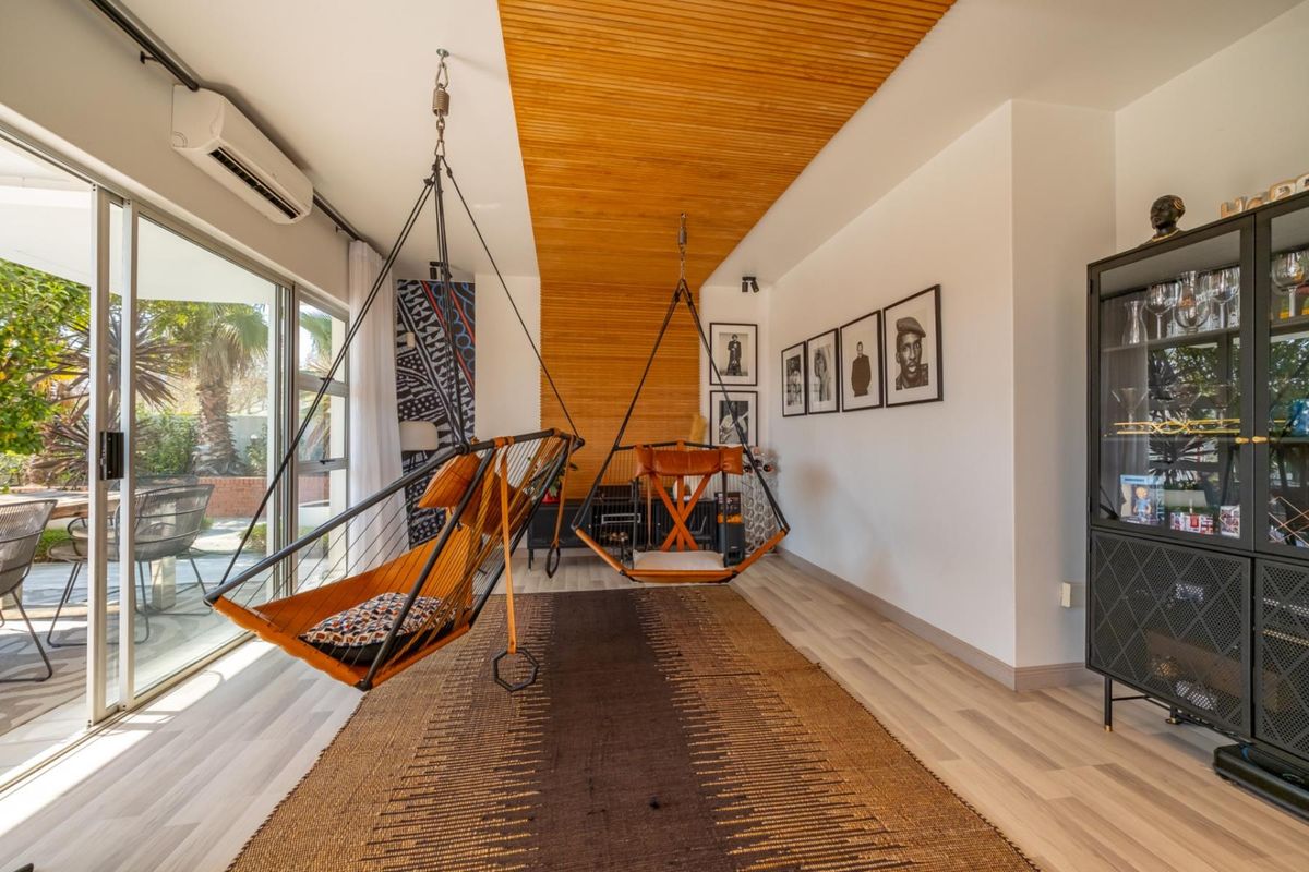 Modern living room featuring a distinctive timber slat ceiling, laminate flooring, and large sliding glass doors providing seamless access to the outdoor patio area.