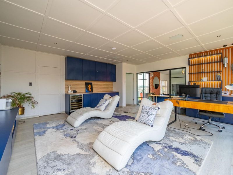 Modern home office featuring custom blue cabinetry, integrated wine cooler, timber slat feature wall, and glass partition, offering a sophisticated workspace.