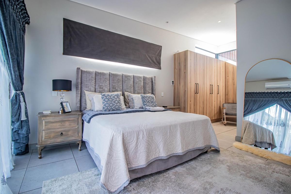 Spacious modern bedroom featuring neutral tiled flooring, extensive built-in wooden cabinetry, and integrated air conditioning for climate control.
