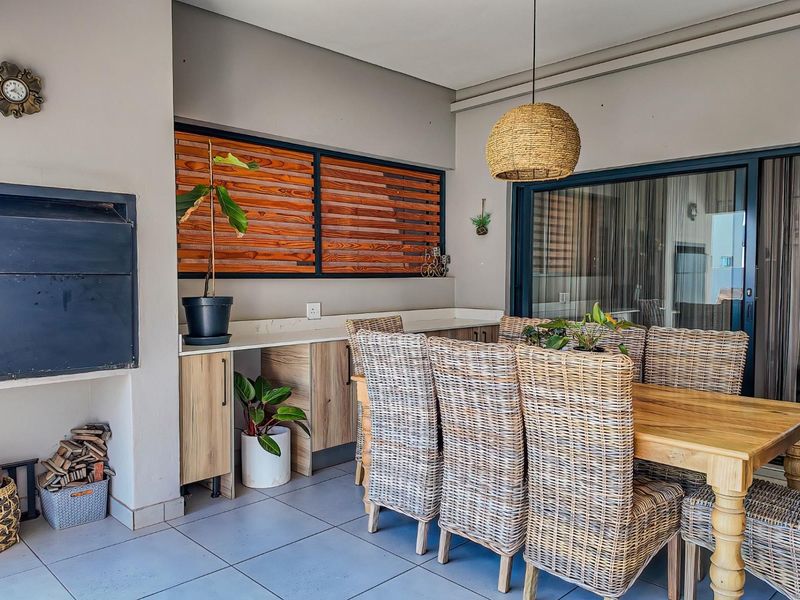 Covered patio area featuring a built-in braai, stone-topped cabinetry, and tiled flooring, providing a functional outdoor entertainment space.