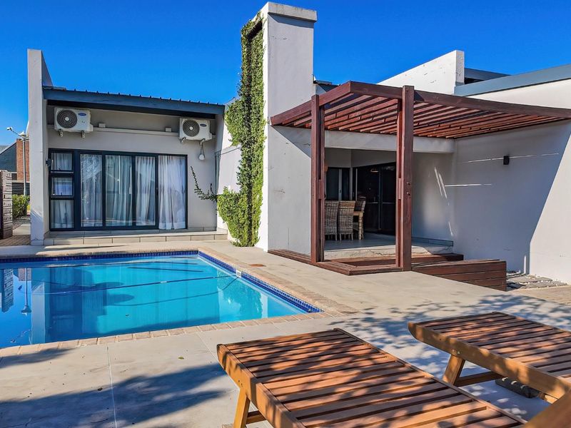 Outdoor pool area featuring a tiled patio, timber pergola, and direct access to the home via sliding glass doors.