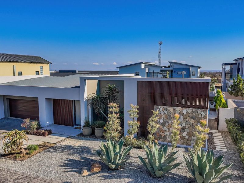 Modern contemporary residence featuring a striking facade with stone cladding, timber slat detailing, a double garage, and a well-maintained landscaped front garden.