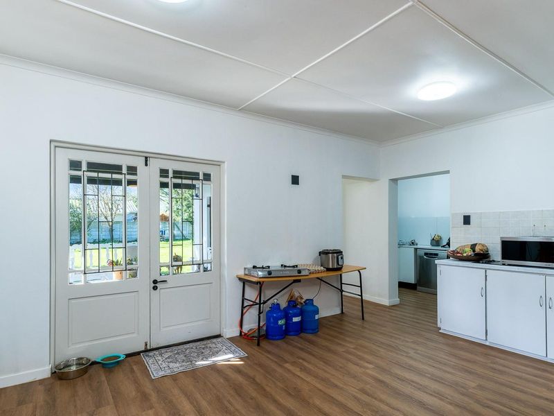 A functional kitchen area featuring laminate flooring, built-in cabinetry with tiled splashbacks, and double glass panel doors leading to the exterior.