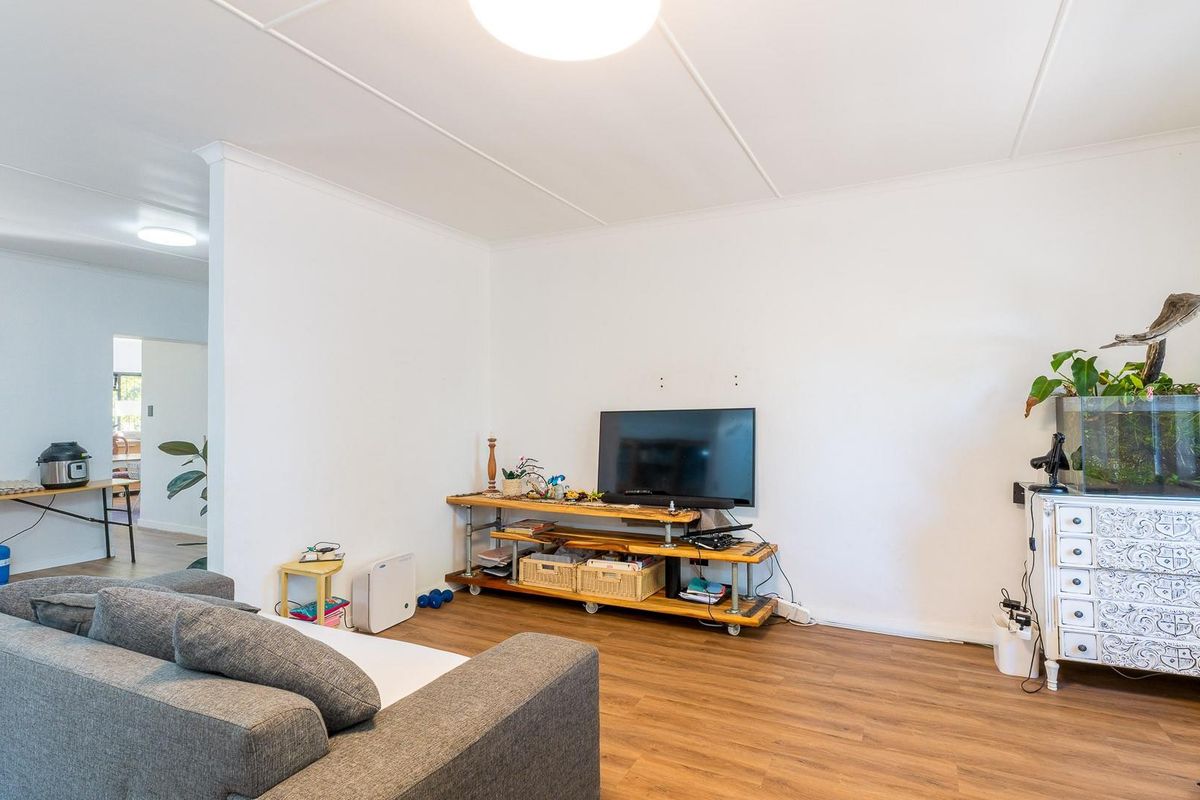 A bright living room featuring wood-look laminate flooring and a coved ceiling, offering a neutral foundation for personalization.