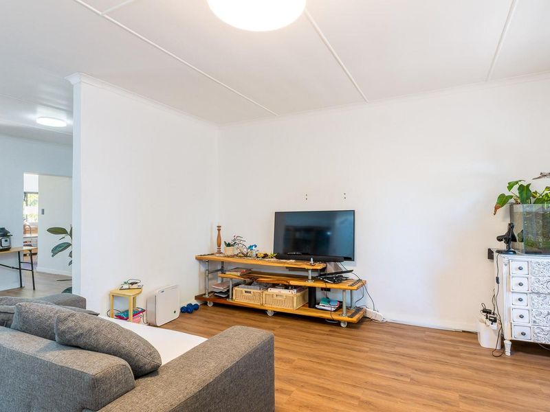 A bright living room featuring wood-look laminate flooring and a coved ceiling, offering a neutral foundation for personalization.