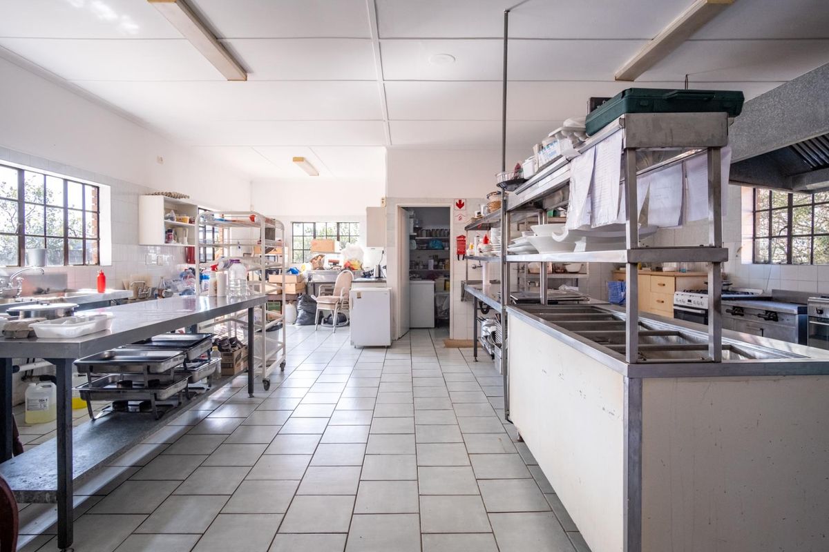 A functional commercial kitchen space featuring stainless steel prep surfaces, tiled flooring, and integrated extraction systems, suitable for professional food preparation.