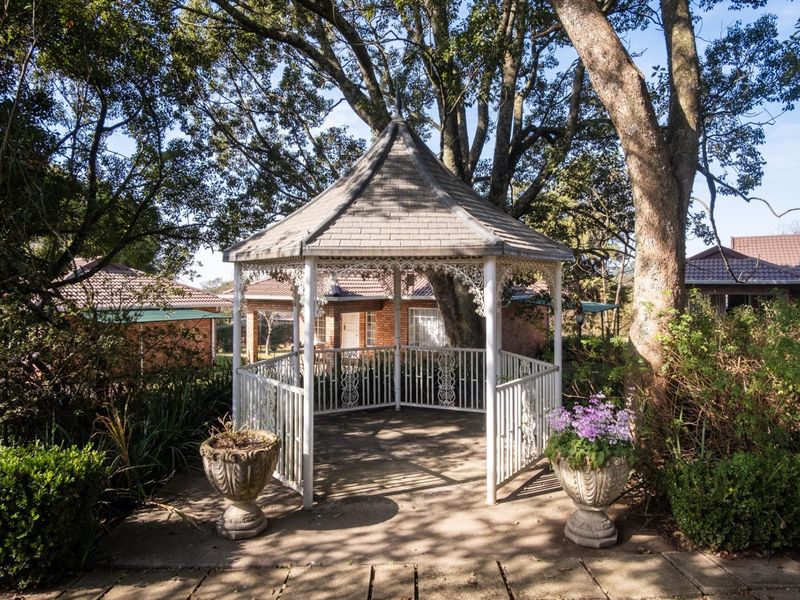 A charming outdoor gazebo set within a lush, landscaped garden area, providing a peaceful and scenic space for relaxation or events.