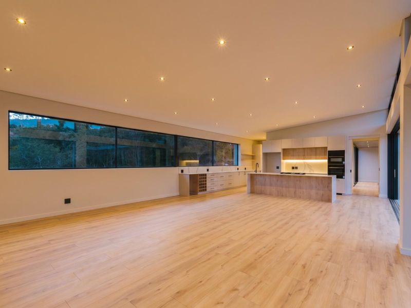 Spacious open-plan living and kitchen area featuring modern cabinetry, integrated appliances, recessed lighting, and large windows with views.