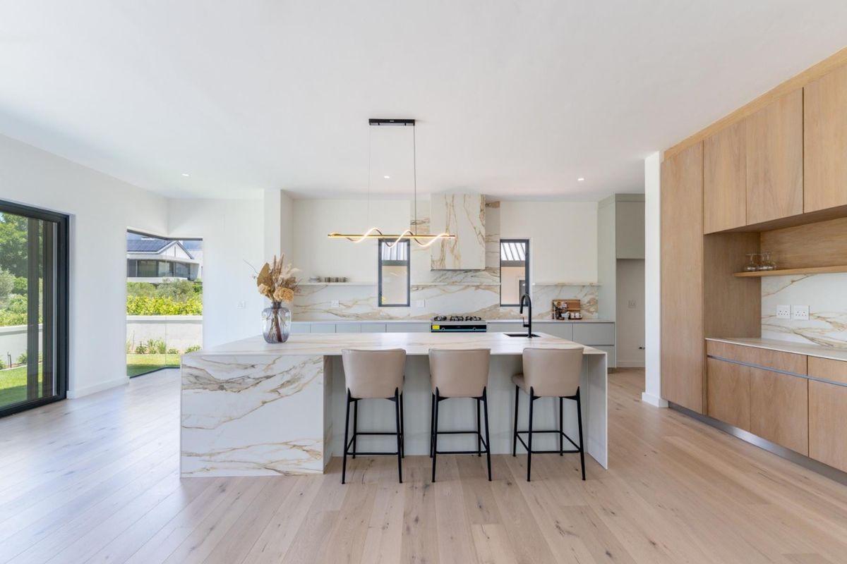 Modern open-plan kitchen featuring a large marble island, high-end cabinetry, integrated appliances, and premium finishes throughout.