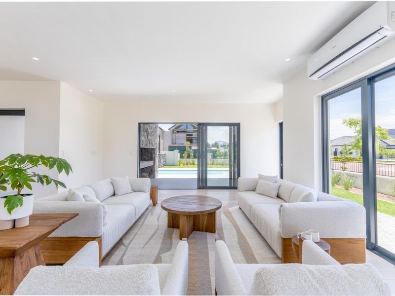 A bright and modern living room featuring tiled floors, recessed lighting, a split-system air conditioner, and large sliding doors opening to the patio.