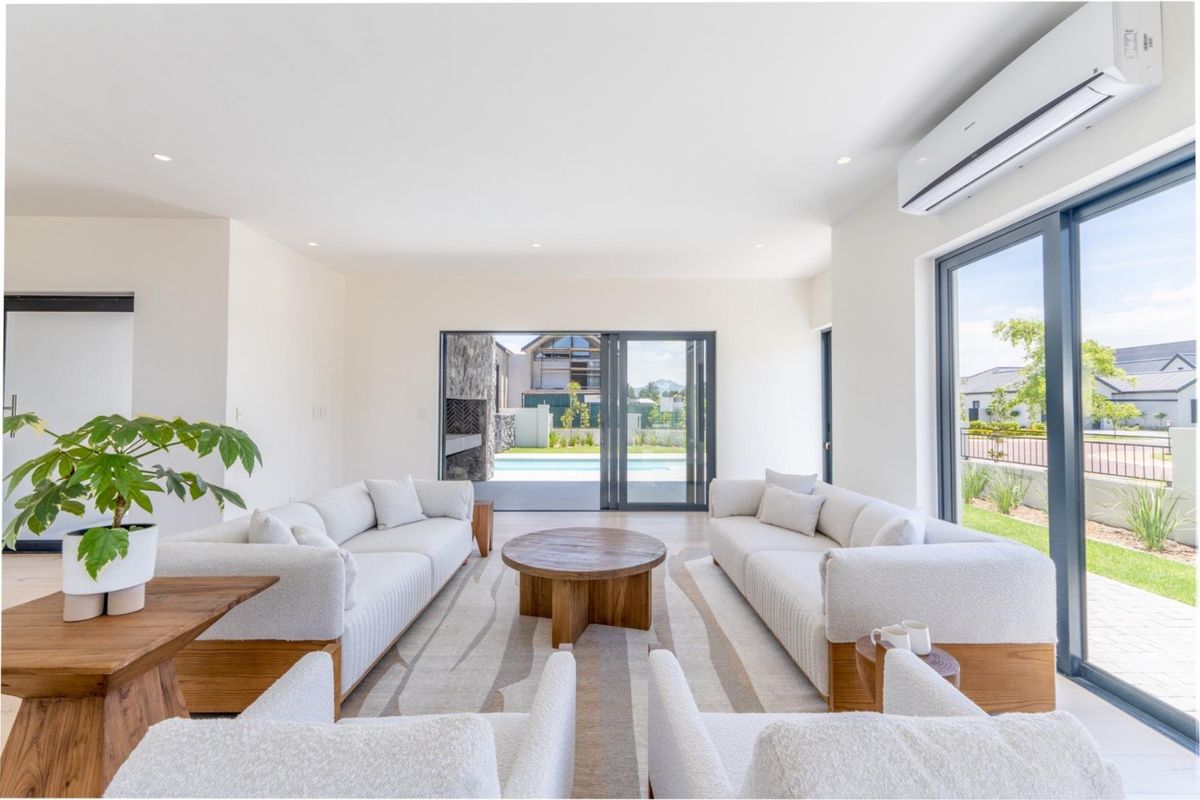 A bright and modern living room featuring tiled floors, recessed lighting, a split-system air conditioner, and large sliding doors opening to the patio.
