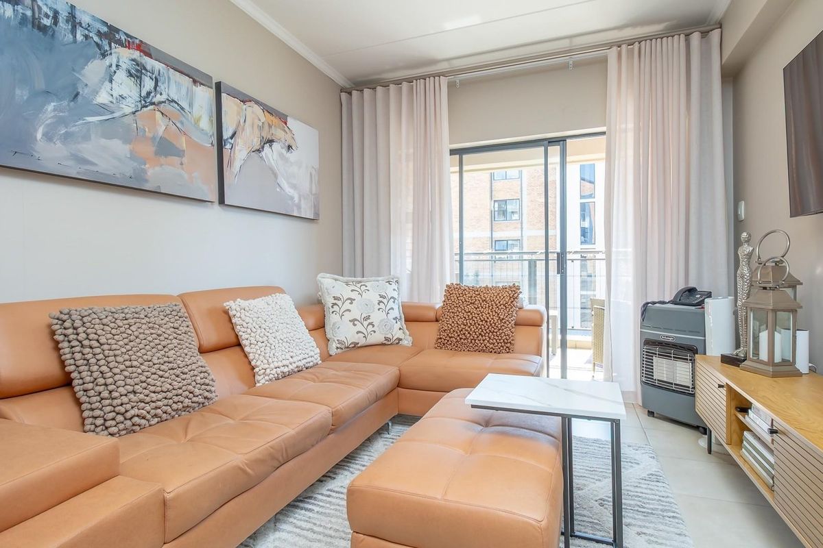 A well-maintained living room featuring tiled flooring and a sliding glass door that provides access to an outdoor balcony area.