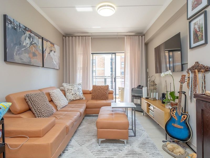 A well-maintained living room featuring tiled flooring, a ceiling light fixture, and a sliding glass door leading to a balcony.