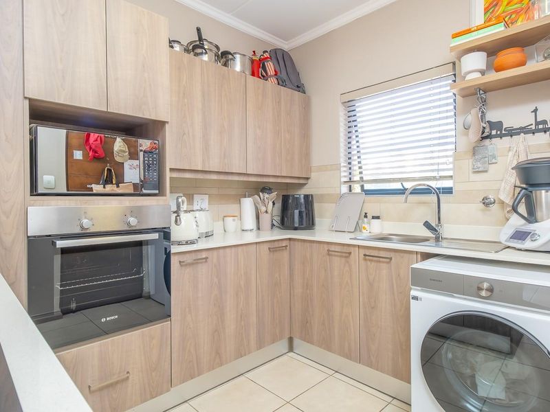 A well-maintained kitchen featuring light wood-finish cabinetry, integrated oven and microwave, tiled backsplash, and a functional layout with ample counter space.