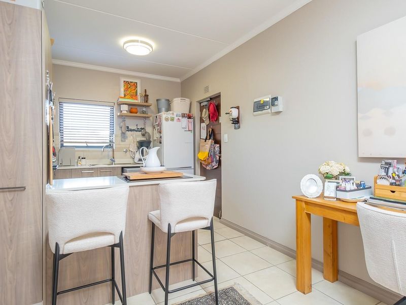 A functional kitchen featuring wood-look cabinetry, tiled flooring, and a breakfast bar area, providing a practical and well-maintained space for daily use.